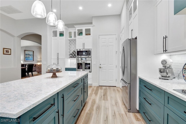 kitchen featuring pendant lighting, light hardwood / wood-style flooring, backsplash, stainless steel appliances, and white cabinets