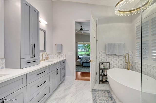 bathroom with vaulted ceiling, hardwood / wood-style floors, a washtub, ceiling fan, and vanity