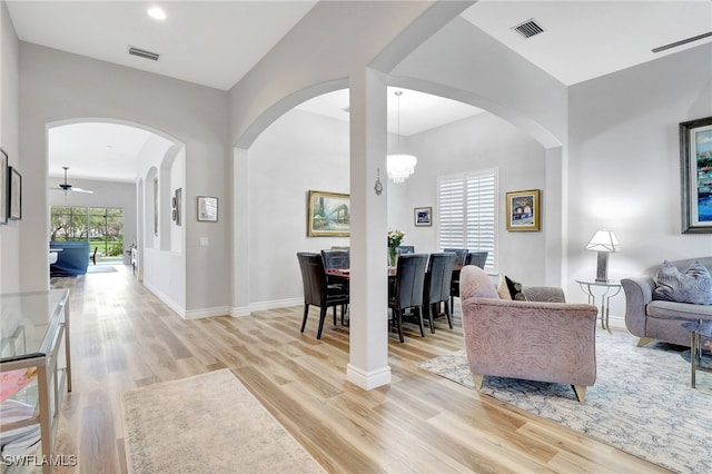 living room featuring light wood-type flooring and ceiling fan with notable chandelier