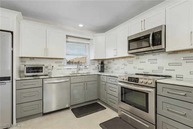 kitchen featuring gray cabinetry, white cabinets, sink, appliances with stainless steel finishes, and light tile patterned flooring