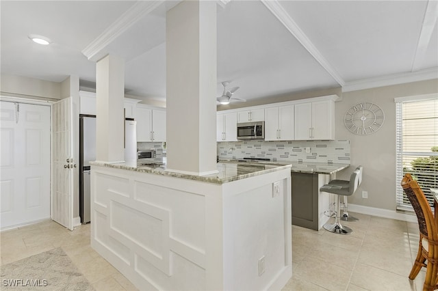 kitchen with light stone countertops, stainless steel microwave, white cabinets, and a center island