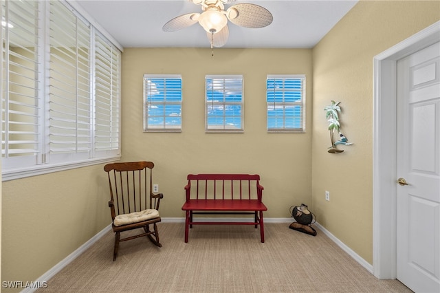 living area featuring light colored carpet and ceiling fan