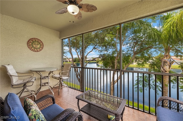 sunroom / solarium with ceiling fan and a water view