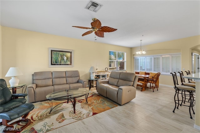 living room with ceiling fan with notable chandelier