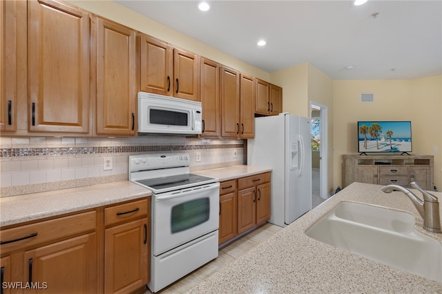 kitchen with backsplash, white appliances, and sink