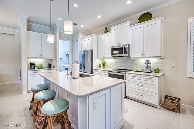 kitchen with white cabinets, backsplash, stainless steel appliances, and a center island with sink