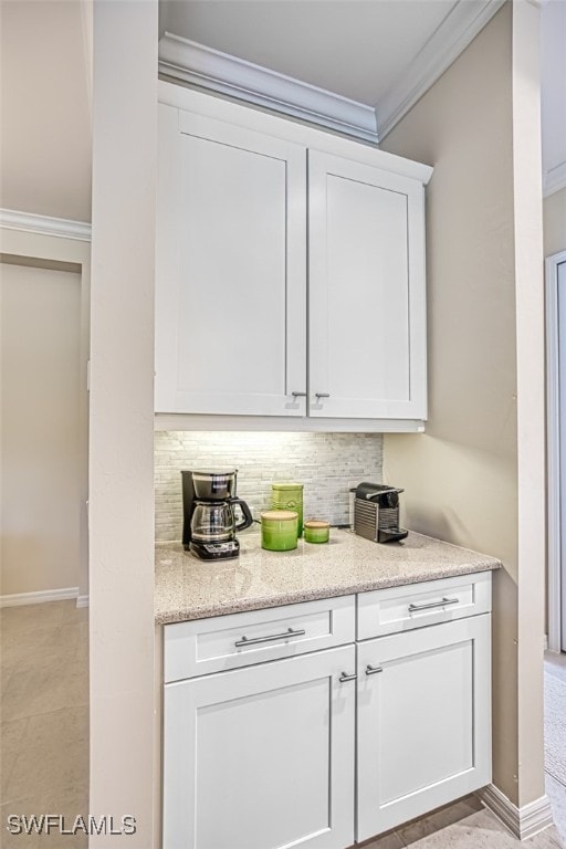 interior space with decorative backsplash, white cabinetry, light stone countertops, and ornamental molding