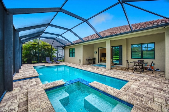 view of swimming pool with an in ground hot tub, a patio, and glass enclosure