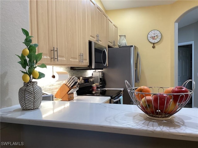 kitchen with stainless steel appliances, light brown cabinets, backsplash, and kitchen peninsula