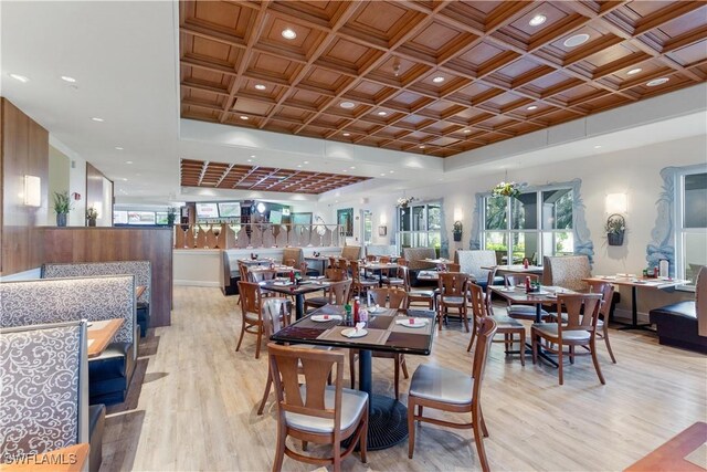 dining room with light hardwood / wood-style floors and coffered ceiling