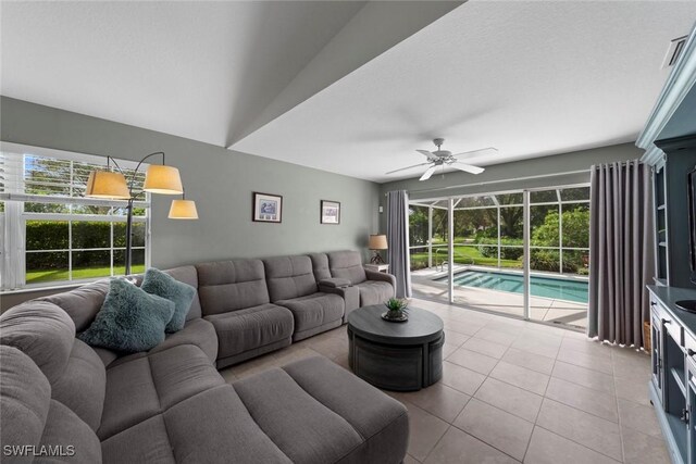 tiled living room with vaulted ceiling, a textured ceiling, and ceiling fan