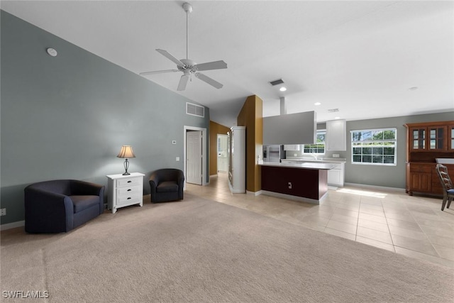 carpeted living room with ceiling fan and high vaulted ceiling