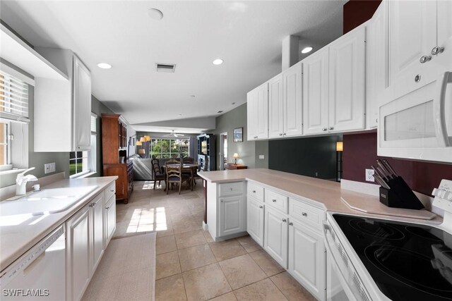 kitchen with white appliances, kitchen peninsula, sink, white cabinetry, and light tile patterned flooring