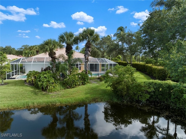 rear view of property featuring glass enclosure, a yard, and a water view