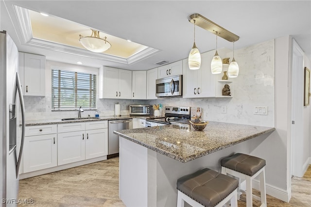 kitchen featuring appliances with stainless steel finishes, light hardwood / wood-style flooring, stone countertops, and pendant lighting