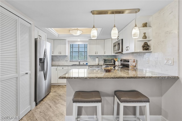 kitchen featuring kitchen peninsula, light wood-type flooring, dark stone countertops, and appliances with stainless steel finishes