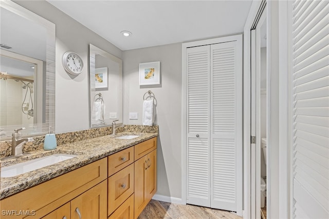 bathroom with toilet, hardwood / wood-style floors, and dual vanity