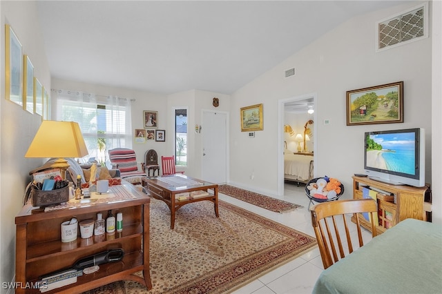 living room with ceiling fan, light tile patterned floors, and vaulted ceiling