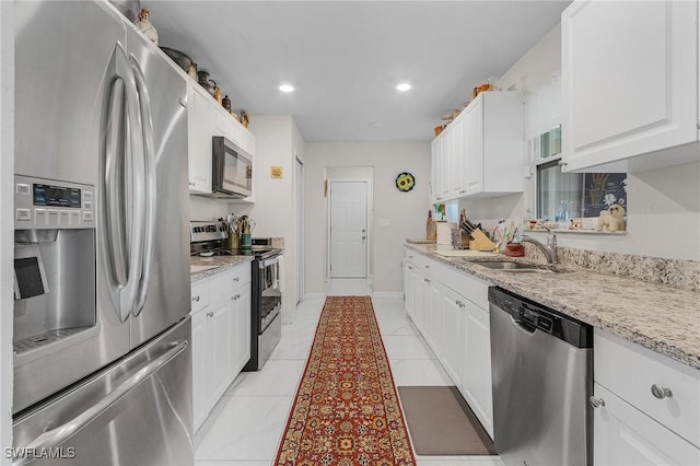 kitchen featuring recessed lighting, appliances with stainless steel finishes, white cabinets, a sink, and light stone countertops