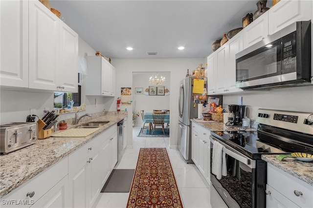 kitchen with appliances with stainless steel finishes, light stone counters, sink, light tile patterned floors, and white cabinets