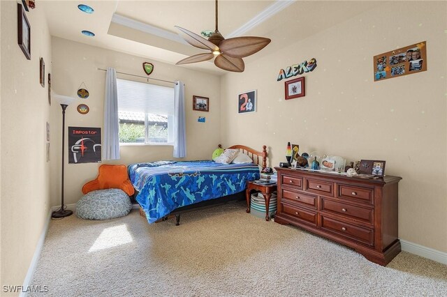 carpeted bedroom featuring ceiling fan, ornamental molding, a raised ceiling, and baseboards