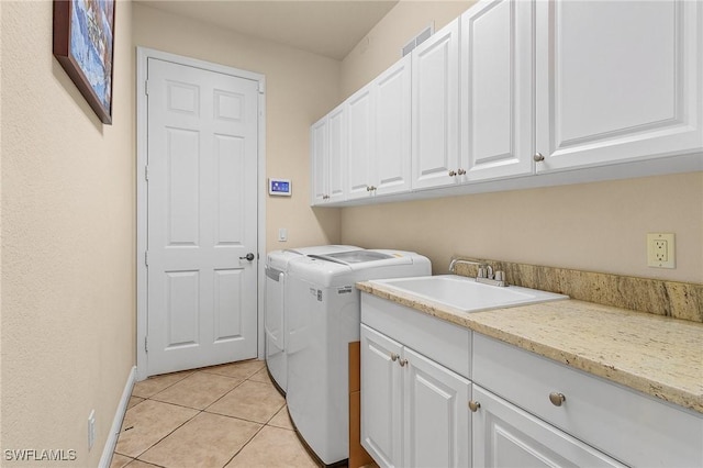 laundry room with washing machine and clothes dryer, light tile patterned floors, cabinet space, a sink, and baseboards