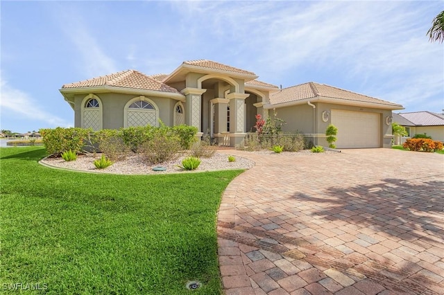 mediterranean / spanish home with a front yard, a tile roof, and an attached garage