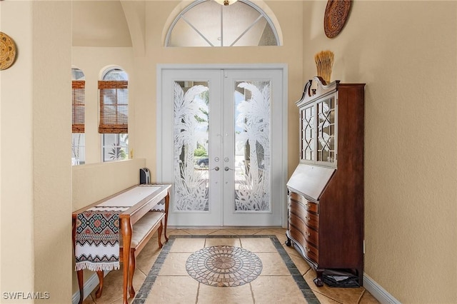 foyer entrance with light tile patterned floors, french doors, and baseboards