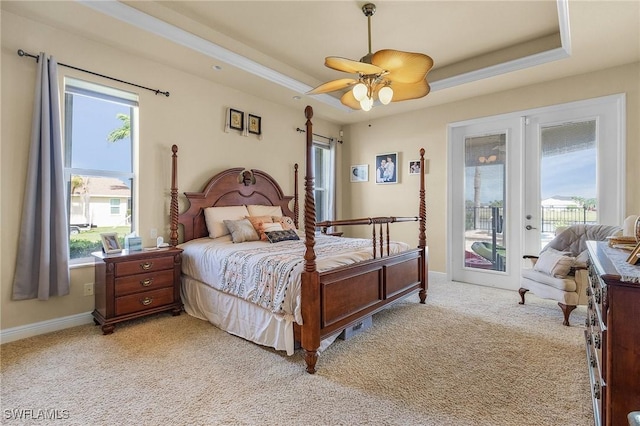 bedroom with access to outside, a tray ceiling, light colored carpet, and french doors