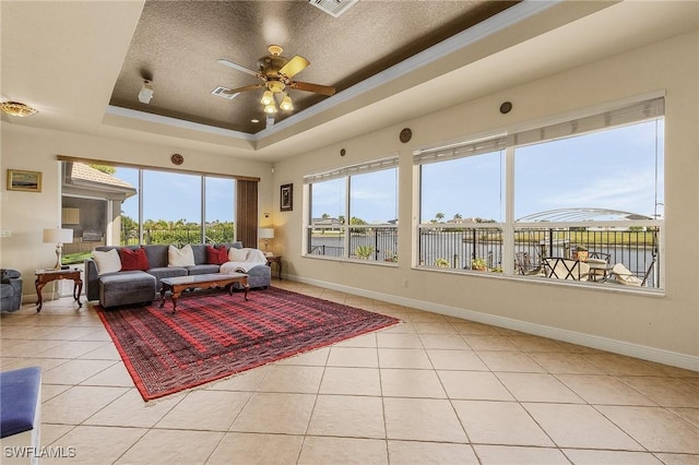 interior space with a raised ceiling, a textured ceiling, baseboards, and light tile patterned floors