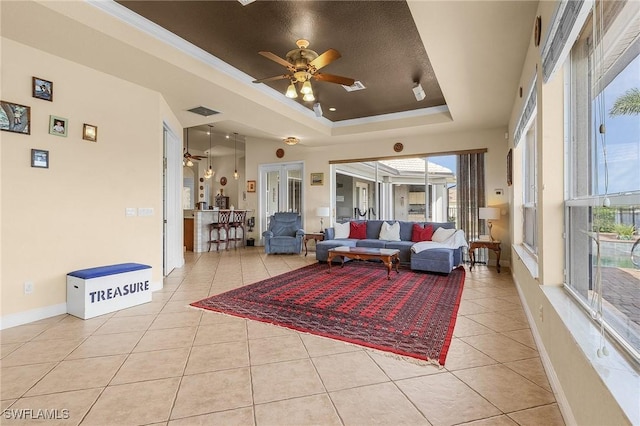 living room with light tile patterned floors, baseboards, a tray ceiling, and a wealth of natural light