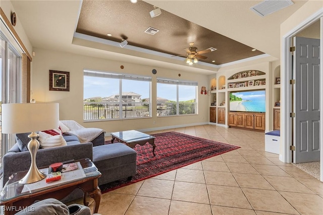 living room with built in features, a tray ceiling, visible vents, and light tile patterned flooring