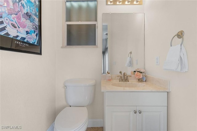 bathroom with toilet, baseboards, and vanity