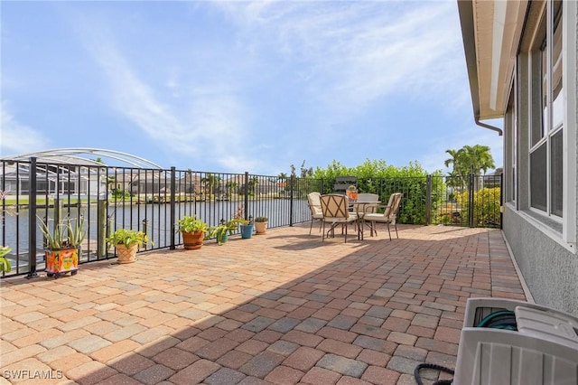 view of patio featuring outdoor dining area, a water view, and fence