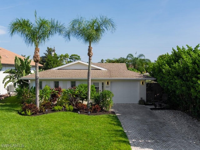 ranch-style house featuring a garage, decorative driveway, and a front yard