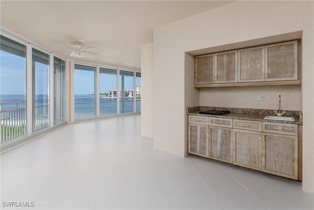 kitchen with ceiling fan, light tile patterned flooring, a wall of windows, and a water view