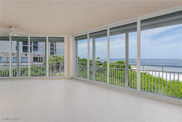 unfurnished sunroom with plenty of natural light, ceiling fan, and a water view