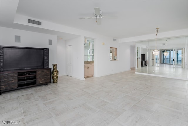 unfurnished living room with ceiling fan with notable chandelier and light tile patterned floors