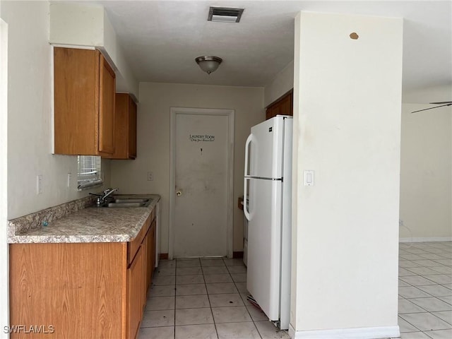 kitchen featuring light tile patterned floors, white fridge, ceiling fan, and sink