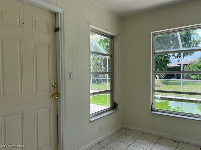 entryway with wooden walls and light tile patterned floors