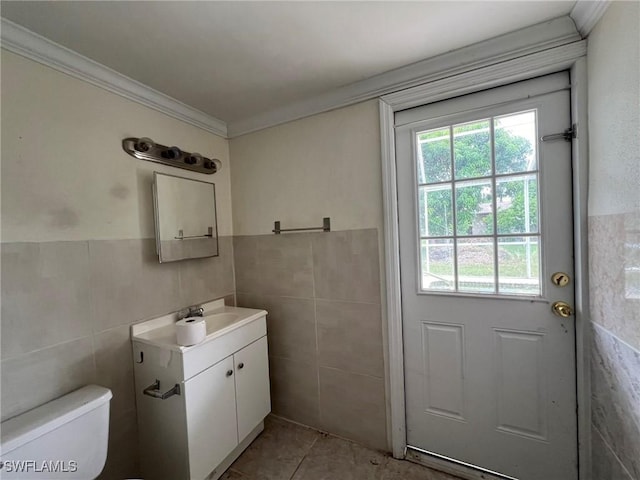 bathroom with vanity, tile patterned floors, toilet, ornamental molding, and tile walls