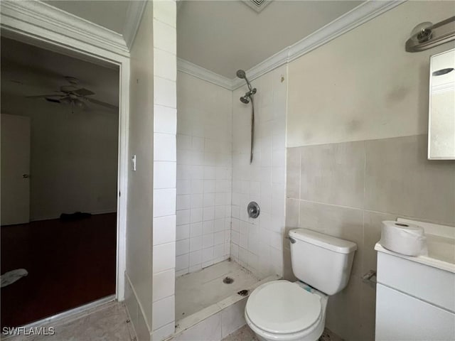 bathroom featuring a tile shower, ceiling fan, toilet, tile walls, and ornamental molding