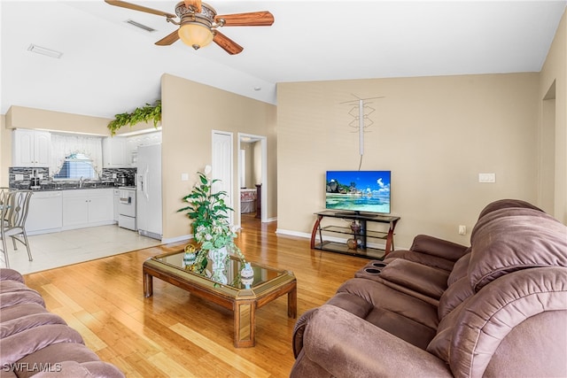 living room with sink, ceiling fan, light hardwood / wood-style floors, and vaulted ceiling