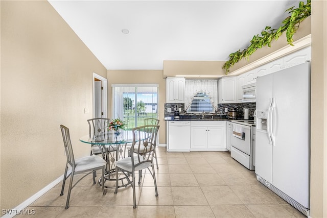 kitchen featuring white appliances, light tile patterned floors, sink, decorative backsplash, and white cabinetry