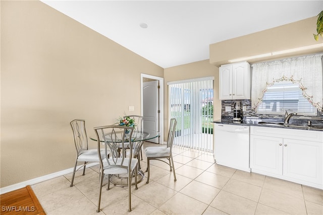 kitchen with white dishwasher, white cabinetry, sink, lofted ceiling, and light tile patterned flooring