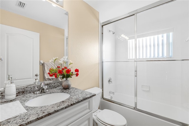 full bathroom featuring shower / bath combination with glass door, vanity, and toilet