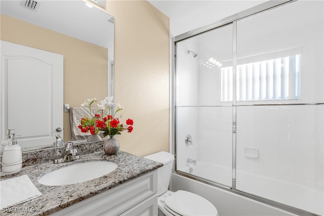 full bathroom featuring toilet, bath / shower combo with glass door, and vanity