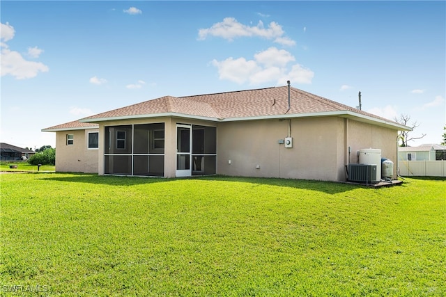 back of house with central AC unit, a sunroom, and a lawn