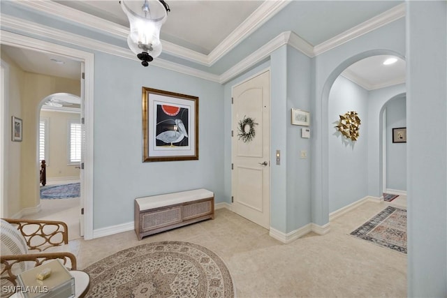 foyer with baseboards, arched walkways, crown molding, and light colored carpet