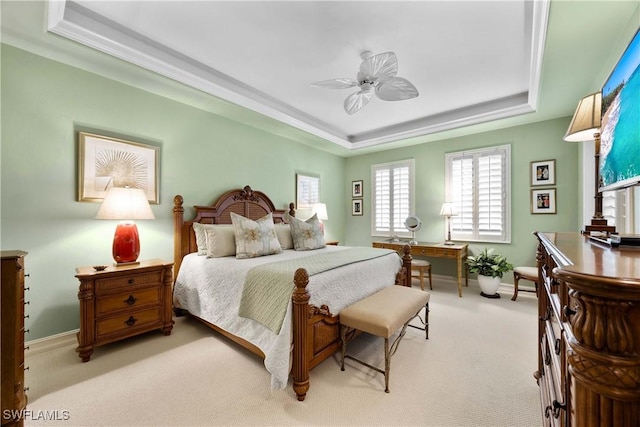 bedroom featuring baseboards, a raised ceiling, a ceiling fan, and light colored carpet